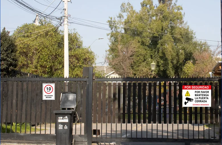 Portón con letrero de velocidad máxima 10 km/h y letrero de seguridad